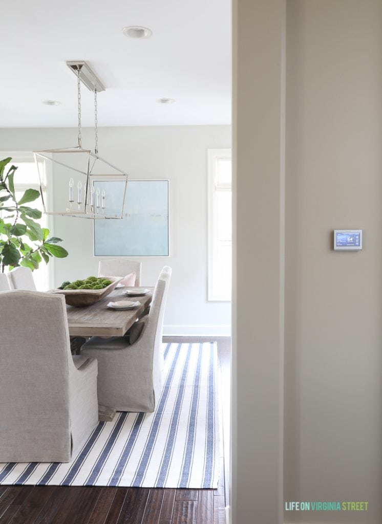 Dining room with the navy striped rug, linen chairs, reclaimed wood table and beach art. 