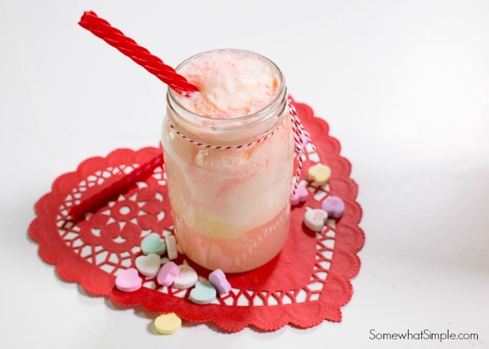 A cupid float drink on a red heart and a red liquorice in it as a straw.