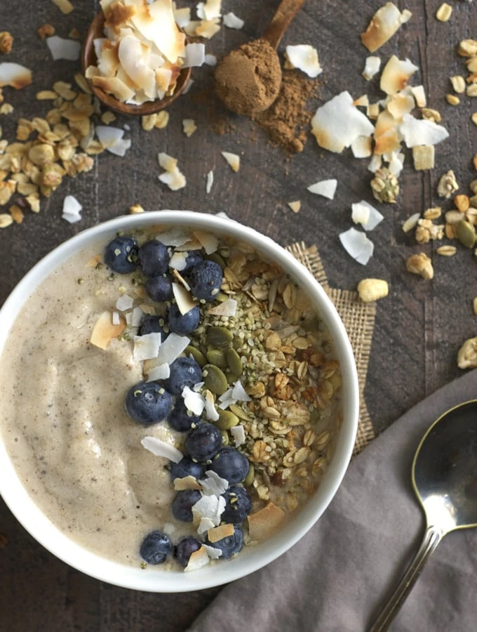 Maple chai smoothie bowl that has grains on the table beside the bowl.