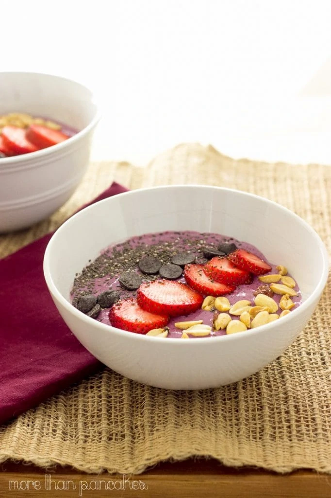 Peanut butter and jelly smoothie bowl on the table with a purple napkin beside it.