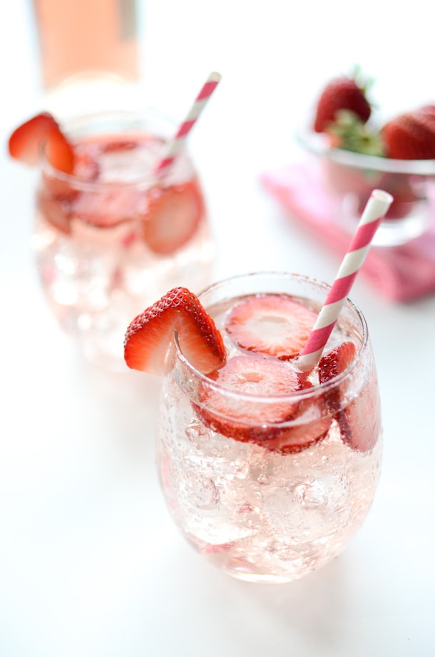Strawberry sangria with strawberries floating inside the drink and red and white straws.