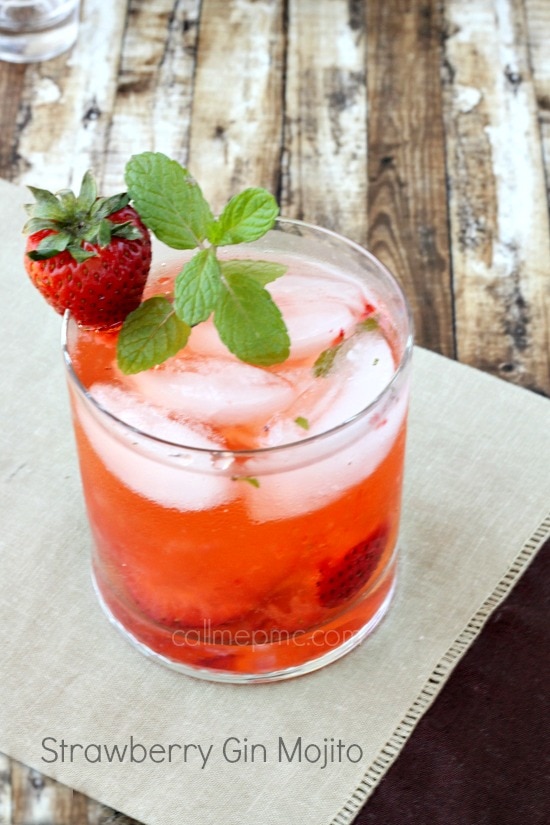 Strawberry gin mojito on the table with a strawberry on the side of the glass and a mint leaf.