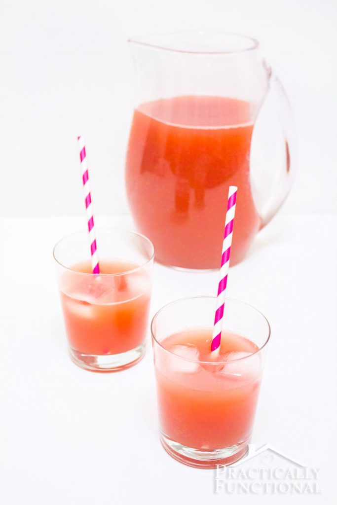 Punch in a jug with it poured into two glasses and purple and white straws in the glasses.
