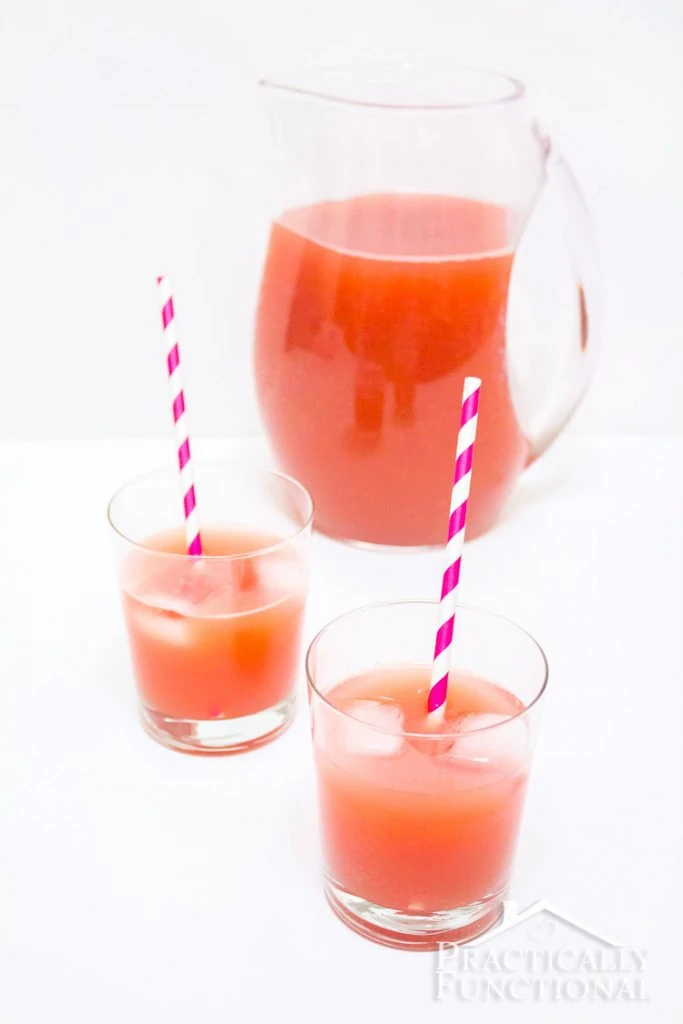 Punch in a jug with it poured into two glasses and purple and white straws in the glasses.