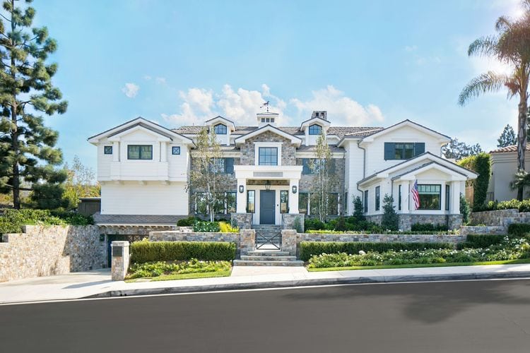 White House with dark gray trim and stone exterior via Kelly Nutt Design