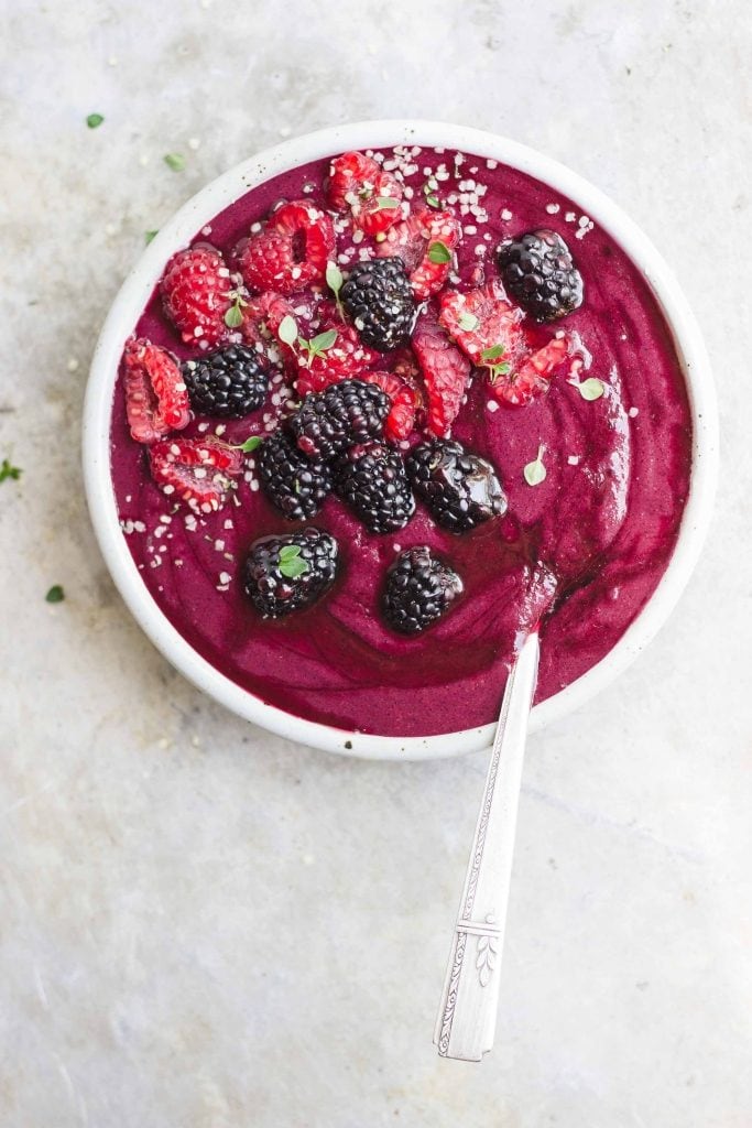 Beet and berry smoothie bowl with a very dark purple color and berries on top.