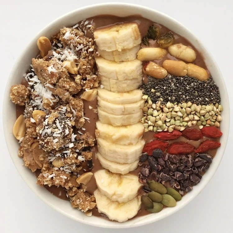 Chocolate Maca Peanut Butter Smoothie Bowl with fresh cut bananas and nuts on top.