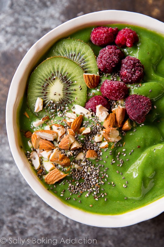 Green smoothie bowl with raspberries, kiwi's and almond on top.