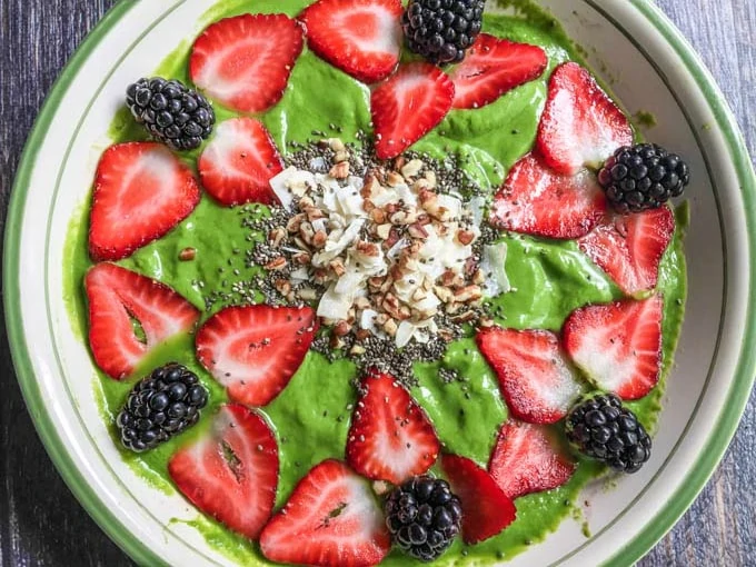 Low carb matcha smoothie bowl in a white and green striped bowl.