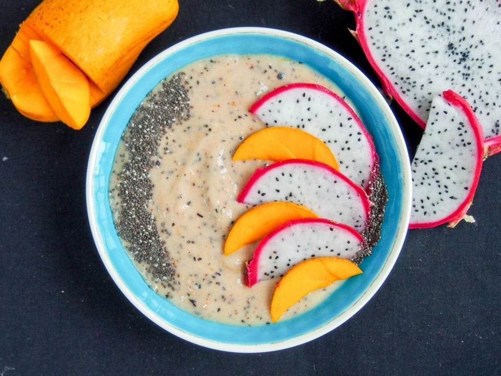 Mango and dragon fruit smoothie bowl that has dragon fruit and mango slices on top.
