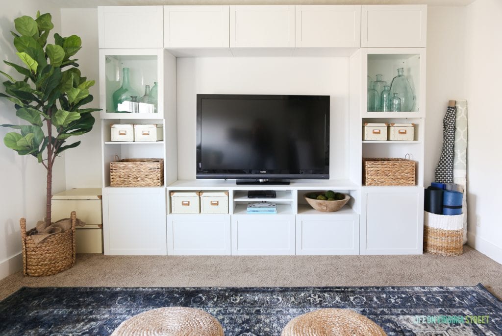 Linen chairs, blue vintage rug, ribbon trimmed roman shades, sisal poufs and Behr Simply White Walls. Love the scalloped light fixture and IKEA BESTA entertainment center!