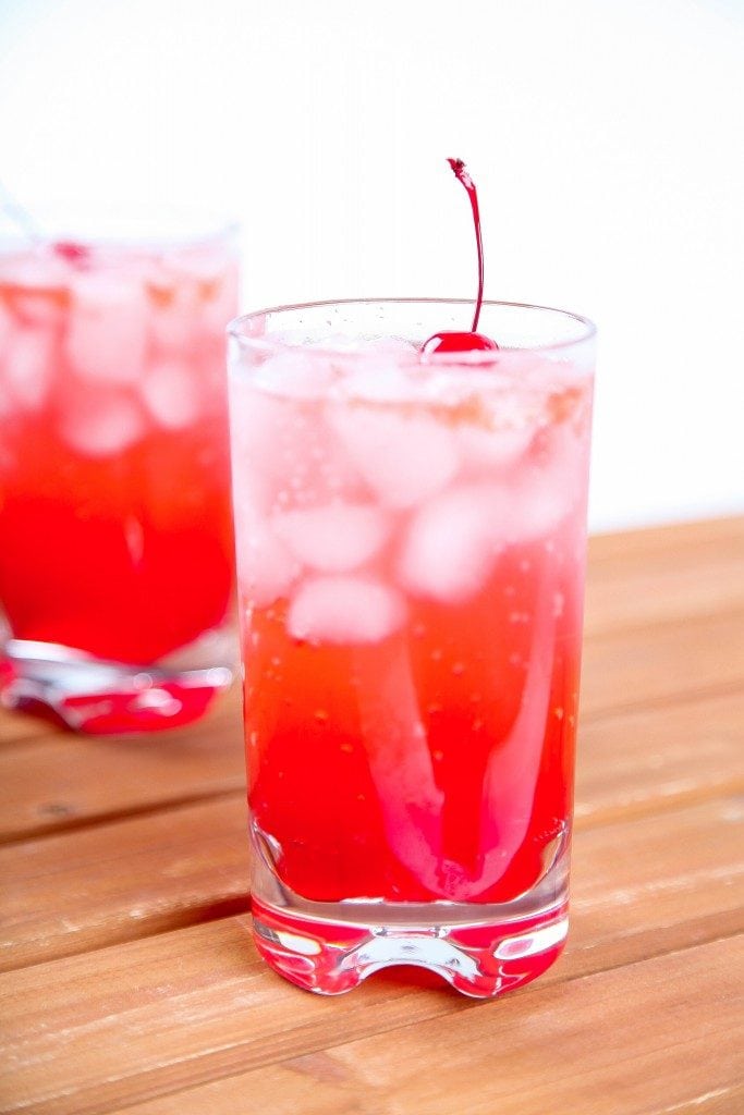 A Shirley Temple cocktail with a cherry and lots of ice.