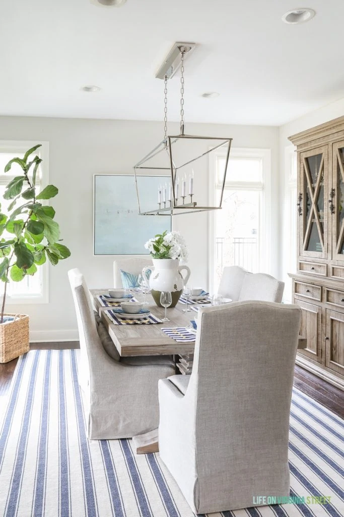 A wooden hutch in the dining room and a large light fixture over the table.