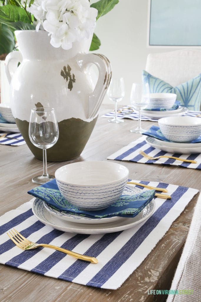 Striped blue and white placemats with white bowls and plates and delicate blue lines on the pottery.
