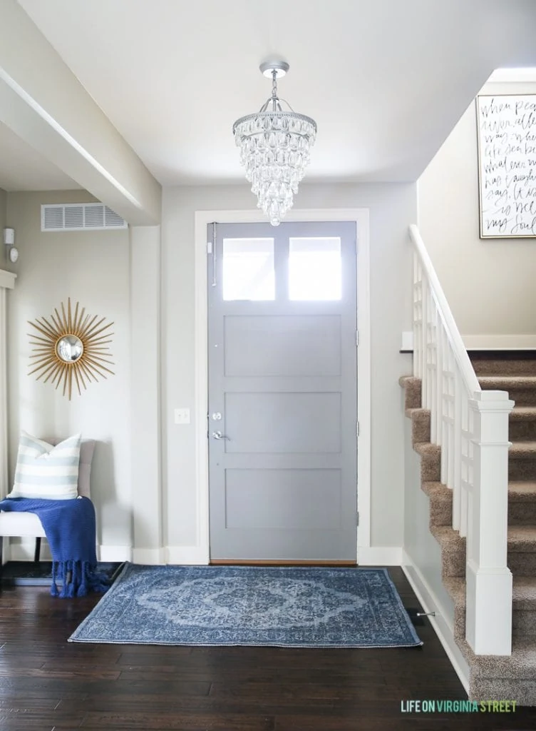 Gorgeous, bright entryway with gray interior front door. Love the blue rug and gold accents! Wall color is Behr Castle Path and door color is Behr Elephant Skin.
