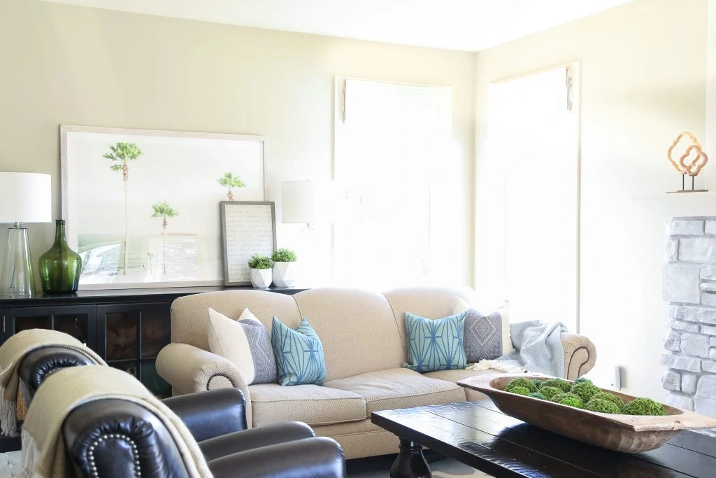 A coastal inspired spring living room with blue, green and white accents. I love the palm tree art! Walls are Behr Castle Path.