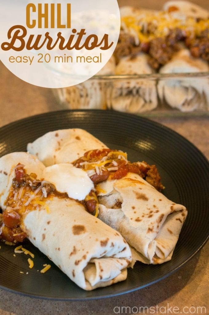 Two chili burritos in a plate on the counter with sour cream on top.