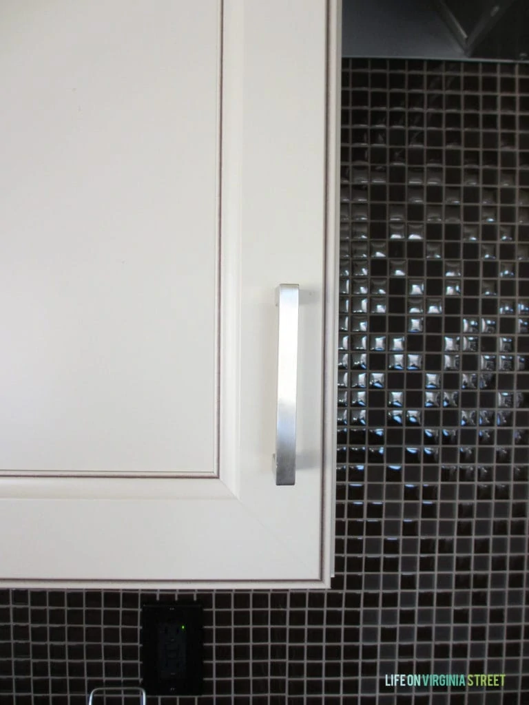 Close up of a white cabinet door with silver handles.