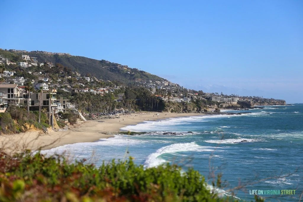 Gorgeous view of the ocean with homes in the background a small cliff/hill.