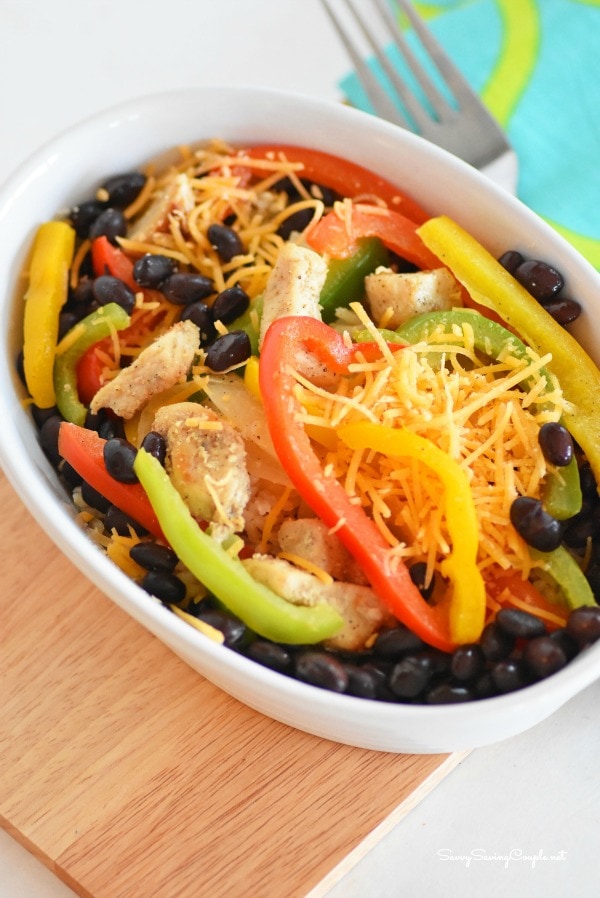 A bowl full of black beans, cheese, green, yellow and red peppers.