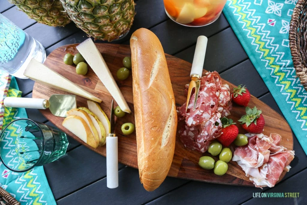 Bread, cheese, olives, and meat on a wooden board.