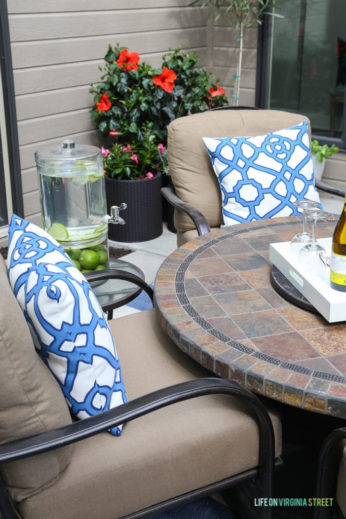 Gorgeous before and after tour of this outdoor courtyard entertaining space. Love the blue and white striped rug, the blue and white trellis pillows, the oleander topiaries, the limes in the beverage dispenser, the white ceramic pineapple, and more!