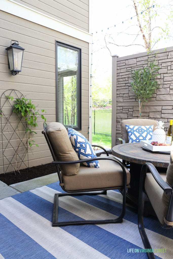 Gorgeous before and after tour of this outdoor courtyard entertaining space. Love the blue and white striped rug, the blue and white trellis pillows, the oleander topiaries, the limes in the beverage dispenser, the white ceramic pineapple, and more!