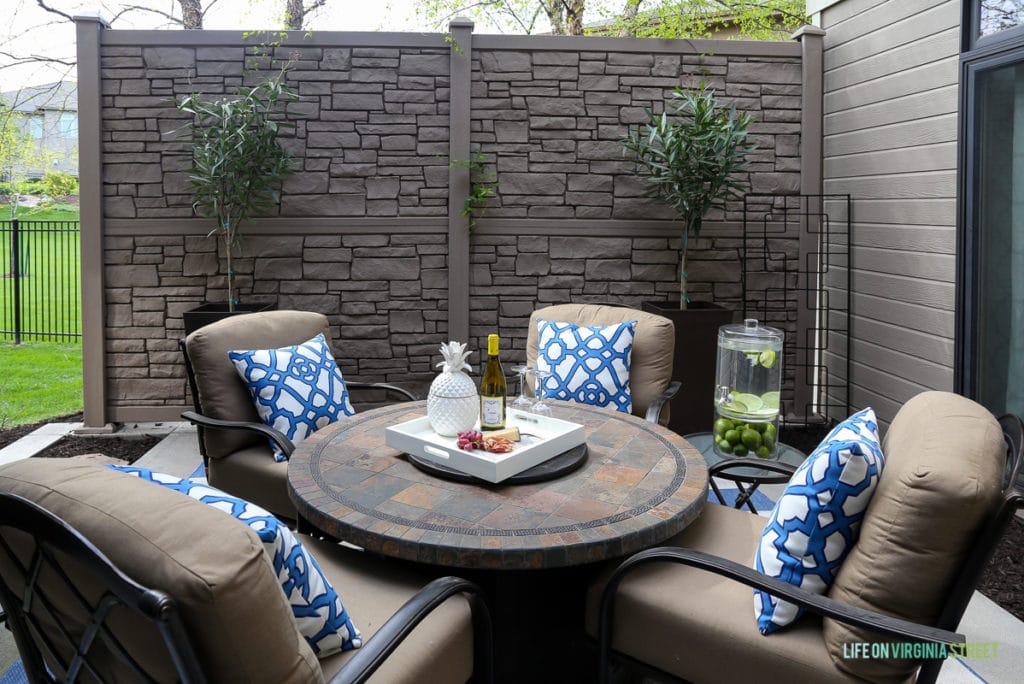 Gorgeous before and after tour of this outdoor courtyard entertaining space. Love the blue and white striped rug, the blue and white trellis pillows, the oleander topiaries, the limes in the beverage dispenser, the white ceramic pineapple, and more!