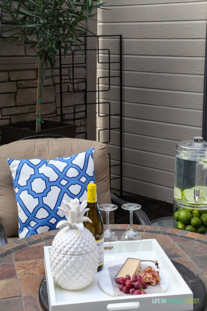 Gorgeous before and after tour of this outdoor courtyard entertaining space. Love the blue and white striped rug, the blue and white trellis pillows, the oleander topiaries, the limes in the beverage dispenser, the white ceramic pineapple, and more!