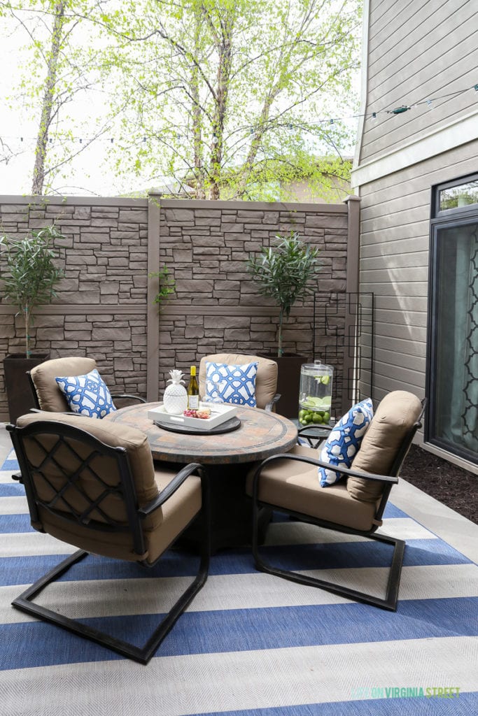 Gorgeous before and after tour of this outdoor courtyard entertaining space. Love the blue and white striped rug, the blue and white trellis pillows, the oleander topiaries, the limes in the beverage dispenser, the white ceramic pineapple, and more!