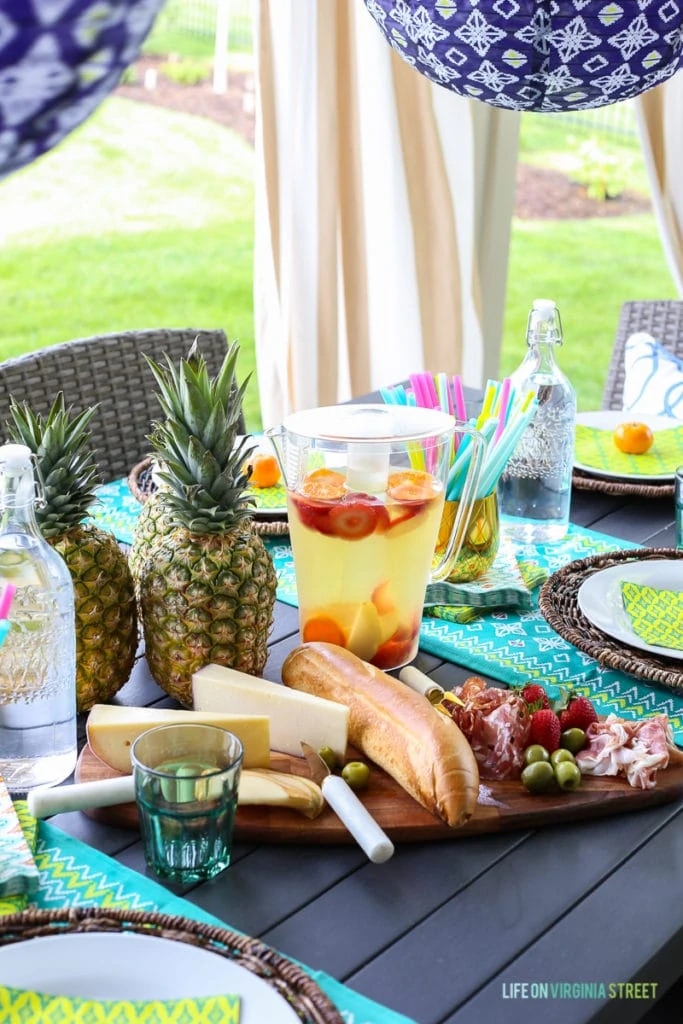 Up close picture of the cheese and meat platter, and a jug full of juice and fresh fruit.