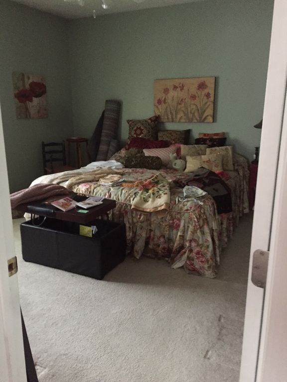 A bedroom with an old bed and items on the bed.