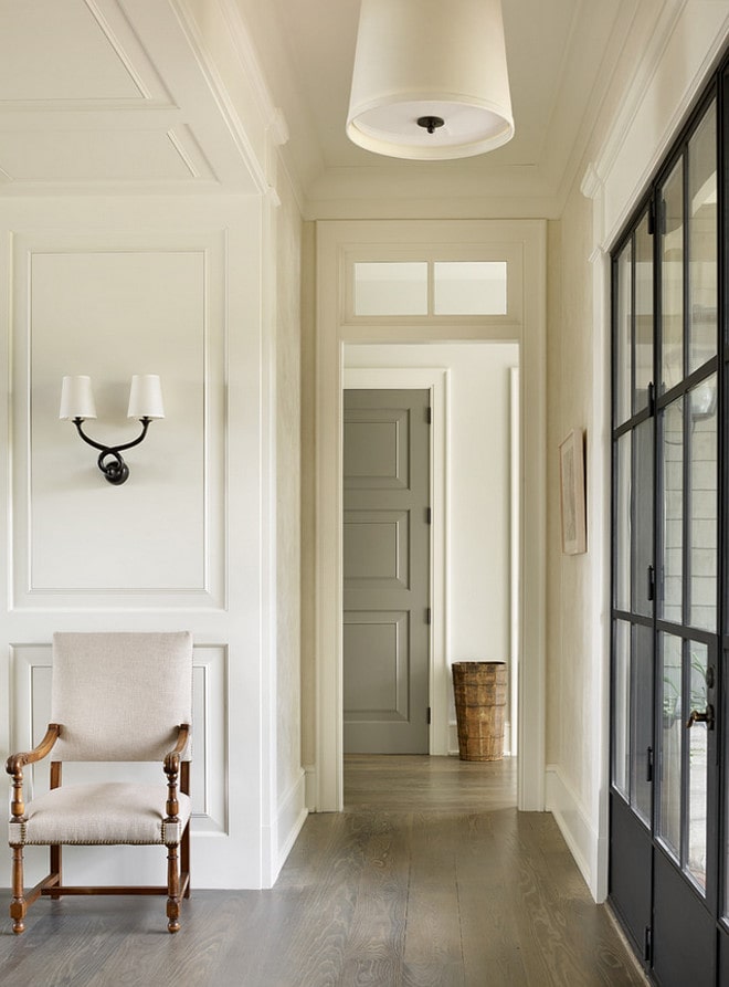 Tan interior front door with darker French doors beside it. A light gray floor color and white chair in the hallway.