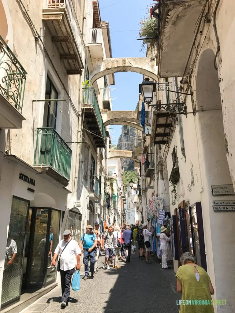 A narrow street with people shopping.