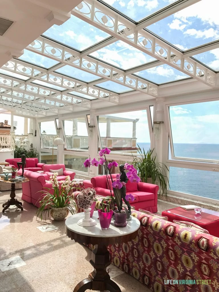 The lobby of the hotel with skylights, pink couches and orchids.