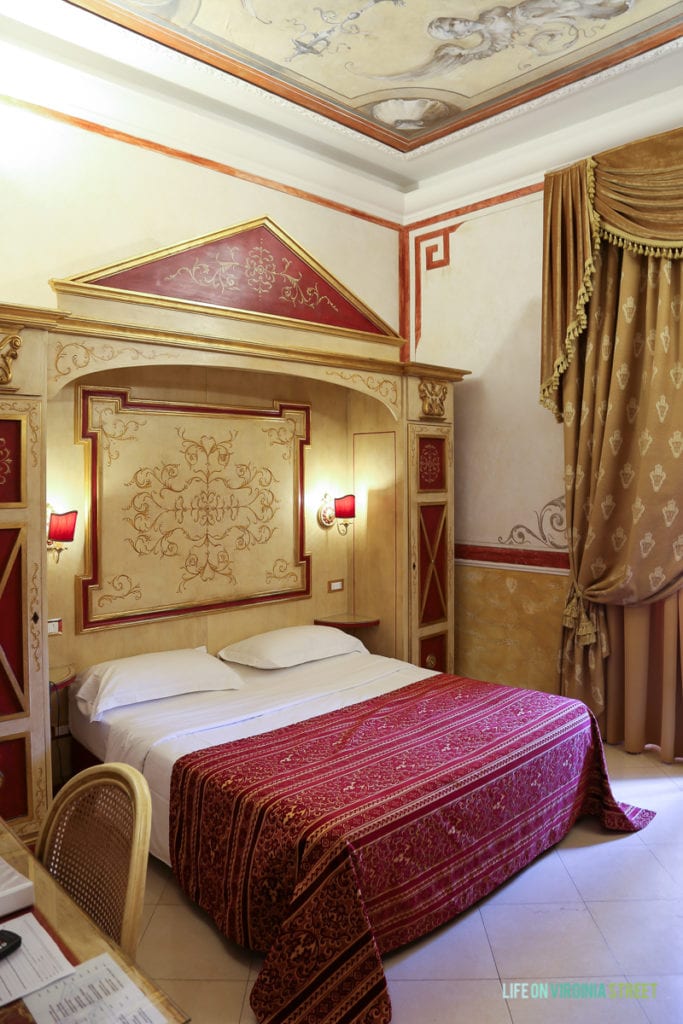A hotel room with fresco painted on the ceiling.