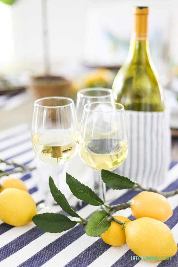 A bottle of white wine and also wine in the glasses with lemons beside it.