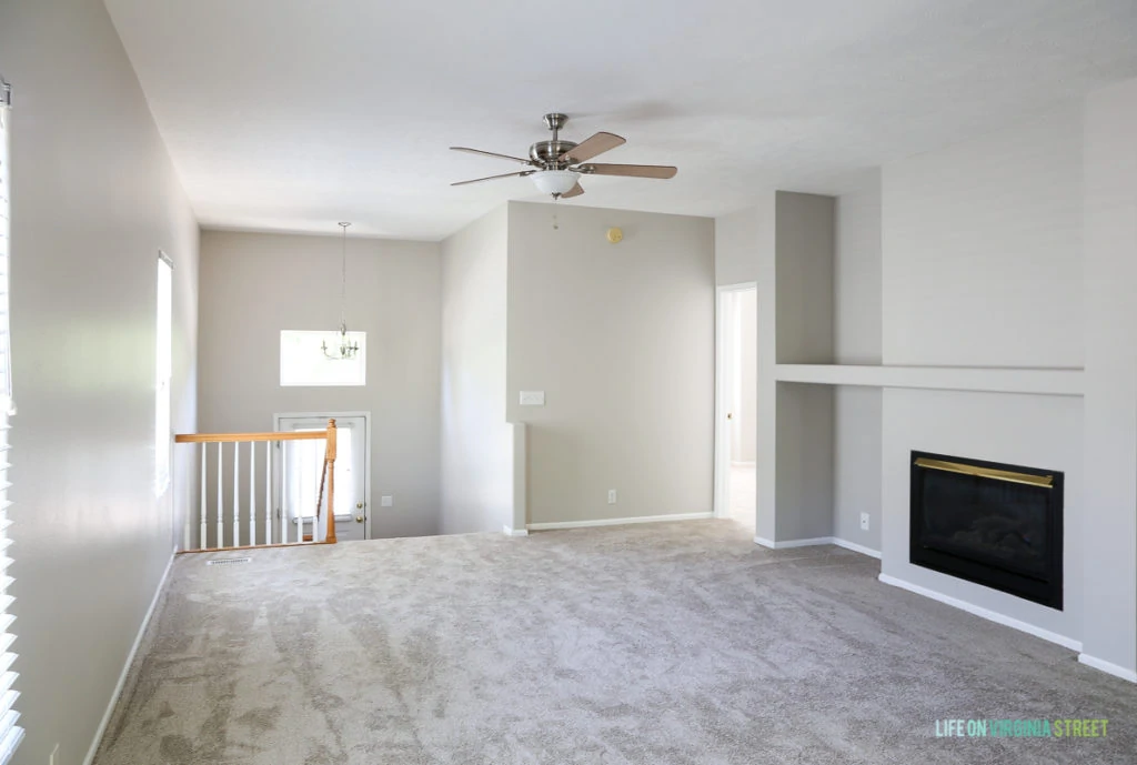The upstairs room with a refreshed carpet and fireplace.   There is a ceiling fan.