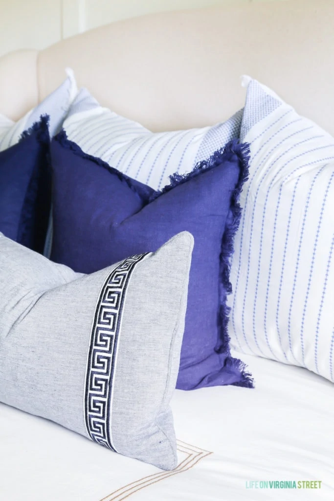 Blue and white throw pillows with Greek key and striped details.