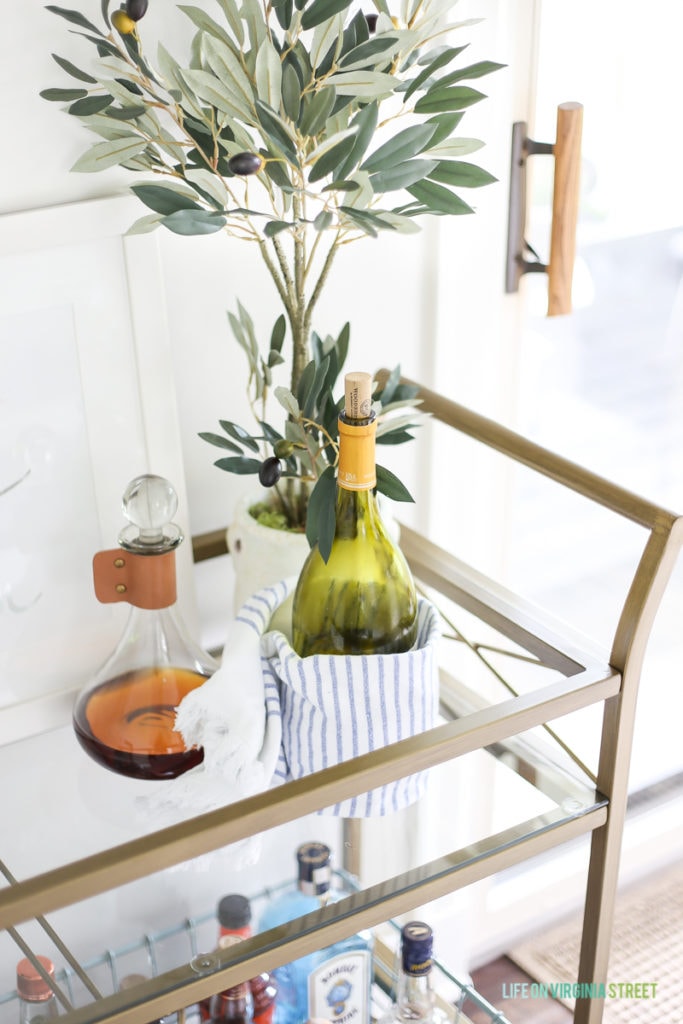 A whisky decanter and a bottle of wine on the bar cart.