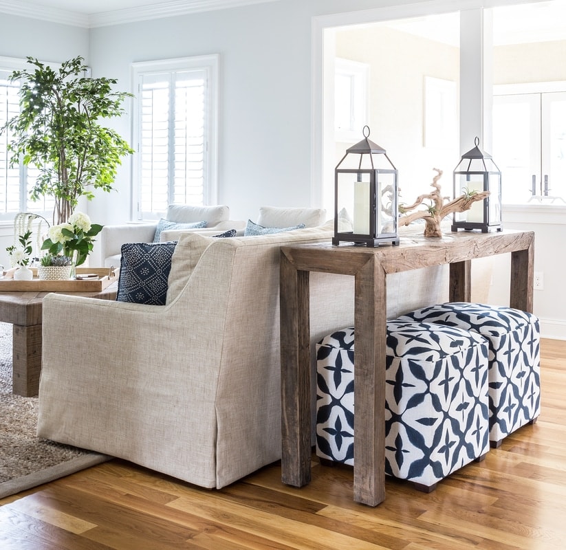 Living room with linen couch, navy and white poufs, driftwood tables, and blue accents.