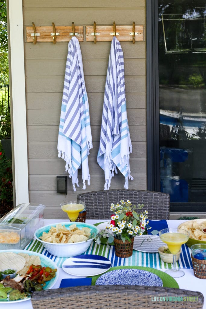 Blue and white blankets hanging outside on hooks by the table.