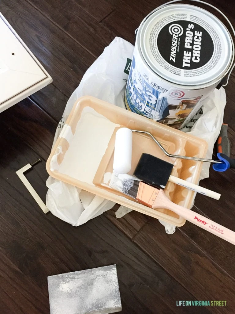 A sanding block, paint tray, paint brush, foam roller, foam brush and Zinsser 1-2-3 primer on the floor ready to paint.