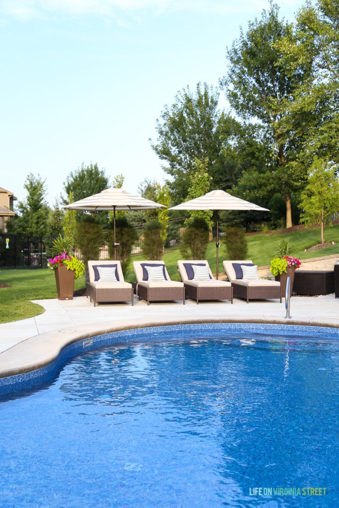 Gorgeous oasis shaped vinyl pool. Striped umbrellas, striped outdoor curtains, lounge chairs, navy blue pillows, striped pillows and planters filled with annuals.