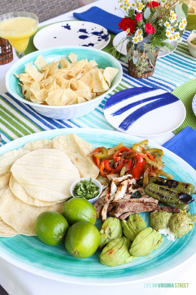 Limes, avocado, and grilled peppers on a plate beside the soft taco shells.