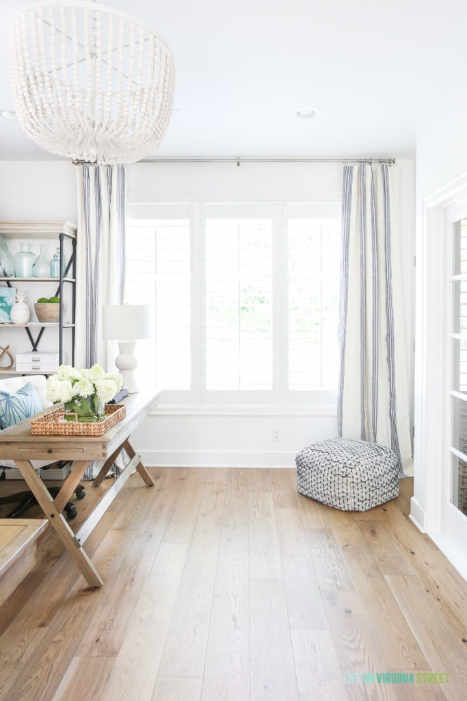 Blue and white striped curtains in office, with a cushion in the corner. The floors are wide plank white oak hardwood floors.