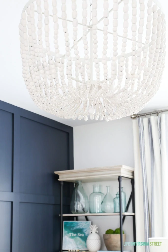 Large white washed beaded chandelier hanging from the ceiling above the desk in the office.