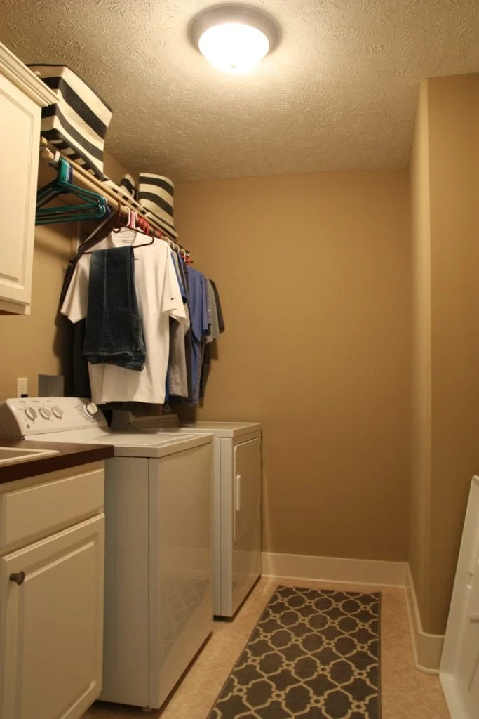 Beige laundry room with clothes hanging above the washer and dryer.