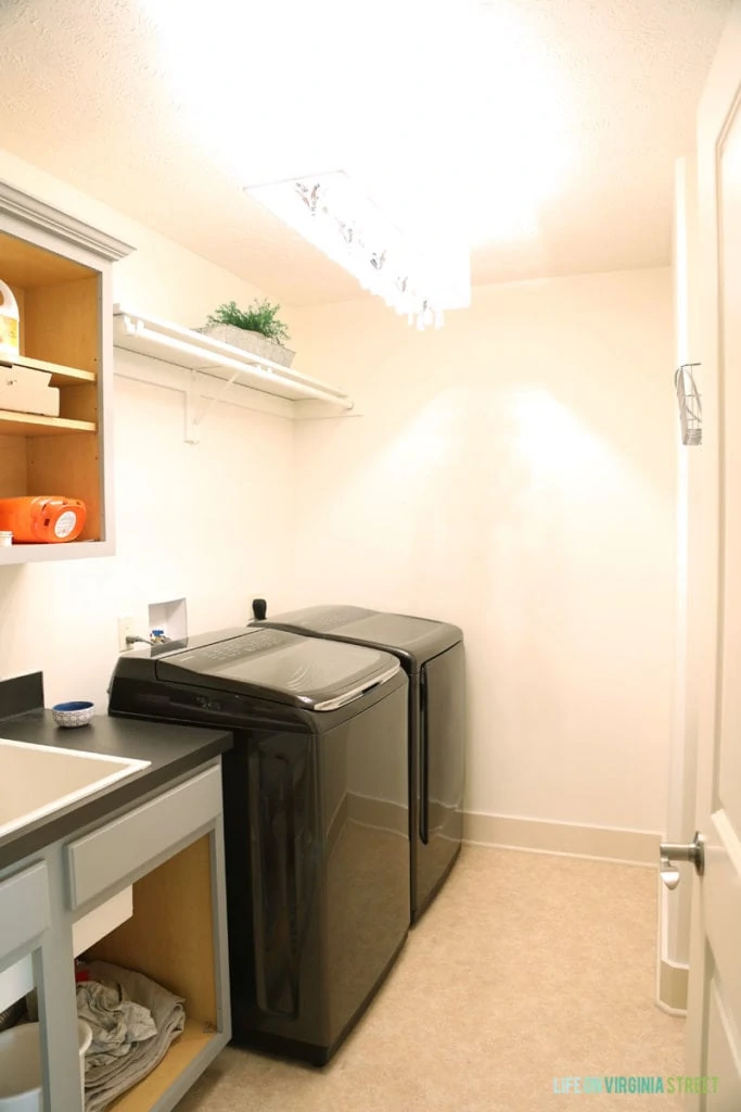 Black washer and dryer and white walls, and grey counter in laundry room.