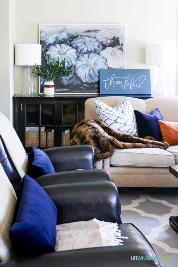 Gorgeous fall living room with navy blue, copper and neutrals. Loving the mix of velvet and faux fur paired with the olive leaves. Also love the large blue pumpkins canvas art and 'thankful' canvas.